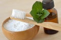 Baking soda in a bowl with a wooden toothbrush and peppermint essential oil - Homemade natural toothpaste