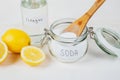 Baking soda in jar, vinegar, lemon, wooden spoon on a white background. The concept of removing stains on clothes