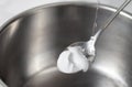 Foaming baking soda slaked with vinegar in a spoon over a metal dish