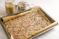 Baking tray with dough from linseed and oat flakes, cut into rhombs and topped with various seeds for healthy pastry snacks, copy