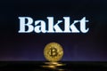 Bakkt logo on a computer screen with a stack of Bitcoin cryptocurency coins.