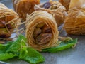 Baklava rolls with whole pistachios on menthe leafs, head on shot, close up