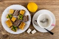 Baklava in white plate, lemon, sugar, cup with tea bag, spoon on saucer on table. Top view