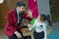 An illusionist and kids is holding a dove in his hands. The magician shows a performance . Focus-illusionist shows children