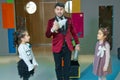 An illusionist and kids is holding a dove in his hands. The magician shows a performance . Focus-illusionist shows children