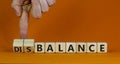 Balance or disbalance symbol. Businessman turns cubes and changes the word disbalance to balance. Beautiful orange background,