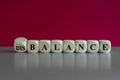 Balance or disbalance symbol. Turned a cube and changes the word disbalance to balance. Beautiful red background, grey table, copy