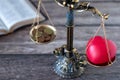 Balance scales with red heart shape and coins with holy bible book