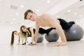 Balance, strength concept. Sporty man and two women do handstand with legs on fit ball. People in sportswear training on Royalty Free Stock Photo