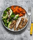 Balanced diet food - grilled turkey, sweet potatoes, kale cabbage, avocado, cucumbers, radish salad on a grey background, top view