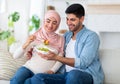 Balanced diet in pregnancy concept. Caring muslim man giving his expectant wife yummy vegetable salad, sitting on sofa Royalty Free Stock Photo