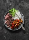 Balanced healthy lunch - beef steak, rice and baked eggplant, pepper, chickpeas stew on a dark background, top view