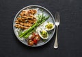 Balanced healthy lunch - rice, asparagus, grilled chicken, boiled egg on a dark background, top view