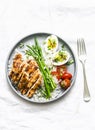 Balanced healthy lunch - rice, asparagus, grilled chicken, boiled egg on a light background, top view