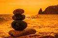 Balanced pebble pyramid on the beach on a sunset time. Sea waves and foam on the background. Selective focus. Zen stones on the Royalty Free Stock Photo