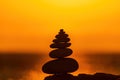 Balanced pebble pyramid silhouette on the beach. Abstract warm sunset bokeh with Sea on the background. Zen stones on Royalty Free Stock Photo