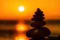 Balanced pebble pyramid silhouette on the beach. Abstract warm sunset bokeh with Sea on the background. Zen stones on Royalty Free Stock Photo
