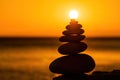 Balanced pebble pyramid silhouette on the beach. Abstract warm sunset bokeh with Sea on the background. Zen stones on Royalty Free Stock Photo