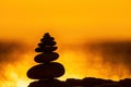 Balanced pebble pyramid silhouette on the beach. Abstract warm sunset bokeh with Sea on the background. Zen stones on Royalty Free Stock Photo