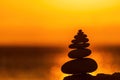 Balanced pebble pyramid silhouette on the beach. Abstract warm sunset bokeh with Sea on the background. Zen stones on Royalty Free Stock Photo