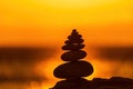 Balanced pebble pyramid silhouette on the beach. Abstract warm sunset bokeh with Sea on the background. Zen stones on Royalty Free Stock Photo