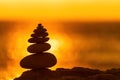 Balanced pebble pyramid silhouette on the beach. Abstract warm sunset bokeh with Sea on the background. Zen stones on Royalty Free Stock Photo