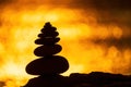 Balanced pebble pyramid silhouette on the beach. Abstract warm sunset bokeh with Sea on the background. Zen stones on Royalty Free Stock Photo