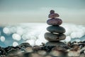 Balanced Pebbles Pyramid on the Beach on Sunny Day and Clear Sky at Sunset. Blue Sea on Background. Selective focus, Bokeh. Zen Royalty Free Stock Photo