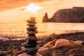 Balanced pebble pyramid on the beach on a sunset time. Sea waves and foam on the background. Selective focus. Zen stones Royalty Free Stock Photo