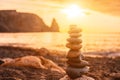 Balanced pebble pyramid on the beach on a sunset time. Sea waves and foam on the background. Selective focus. Zen stones Royalty Free Stock Photo