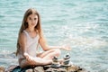 Woman with daughter bilds stones pyramid on seashore on a sunny day on the blue sea background. Happy family holidays Royalty Free Stock Photo