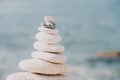 Pyramid stones on the seashore on a sunny day on the blue sea background. Happy holidays. Pebble beach, calm sea, travel