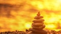 Balanced rock pyramid on pebbles beach. Golden sea bokeh on back