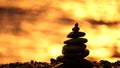 Balanced rock pyramid on pebbles beach. Golden sea bokeh on background. Selective focus, zen stones on sea beach