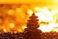 Balanced rock pyramid on pebbles beach. Golden sea bokeh on background. Selective focus, zen stones on sea beach Royalty Free Stock Photo