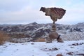 Balanced rocks in a snowy-covered meadow against the backdrop of mountains