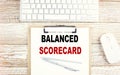 BALANCED SCORECARD text on a clipboard with keyboard on wooden background