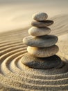 Balanced stack of smooth stones on raked sand forming concentric circles creating a serene and peaceful zen garden atmosphere with Royalty Free Stock Photo