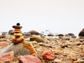 Balanced stone pyramid on sea shore, waves in background. Colorful flat stones Royalty Free Stock Photo