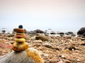 Balanced stone pyramid on sea shore, waves in background. Colorful flat stones Royalty Free Stock Photo