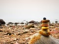 Balanced stone pyramid on sea shore, waves in background. Colorful flat stones Royalty Free Stock Photo