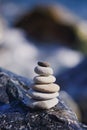 Balanced stone pyramid on shore of blue water. Spa stones treatment scene, zen like concepts. Pebble tower on the seaside. Royalty Free Stock Photo