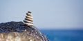 Balanced stone pyramid on shore of blue water. Spa stones treatment scene, zen like concepts. Pebble tower on the seaside.