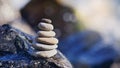 Balanced stone pyramid on shore of blue water. Spa stones treatment scene, zen like concepts. Pebble tower on the seaside. Royalty Free Stock Photo