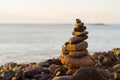 Balanced stone pyramide on shore of the ocean at dawn. Sea pebbles tower closeup symbolizing stability, zen, harmony Royalty Free Stock Photo