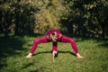 Balancing girl in red sportswear doing yoga pose on the alley in the autumn park