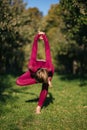 Balancing girl in red sportswear doing yoga pose on the alley in the autumn park