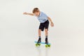 Balancing. Playful, active kid, boy riding on skateboard over grey studio background. Concept of game, childhood Royalty Free Stock Photo