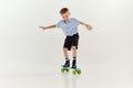 Balancing. Playful, active kid, boy riding on skateboard over grey studio background. Concept of game, childhood Royalty Free Stock Photo