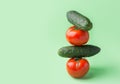 Balancing stack of fresh raw organic tomatoes cucumbers in pyramid on lettuce green background. Balanced diet vegan Royalty Free Stock Photo